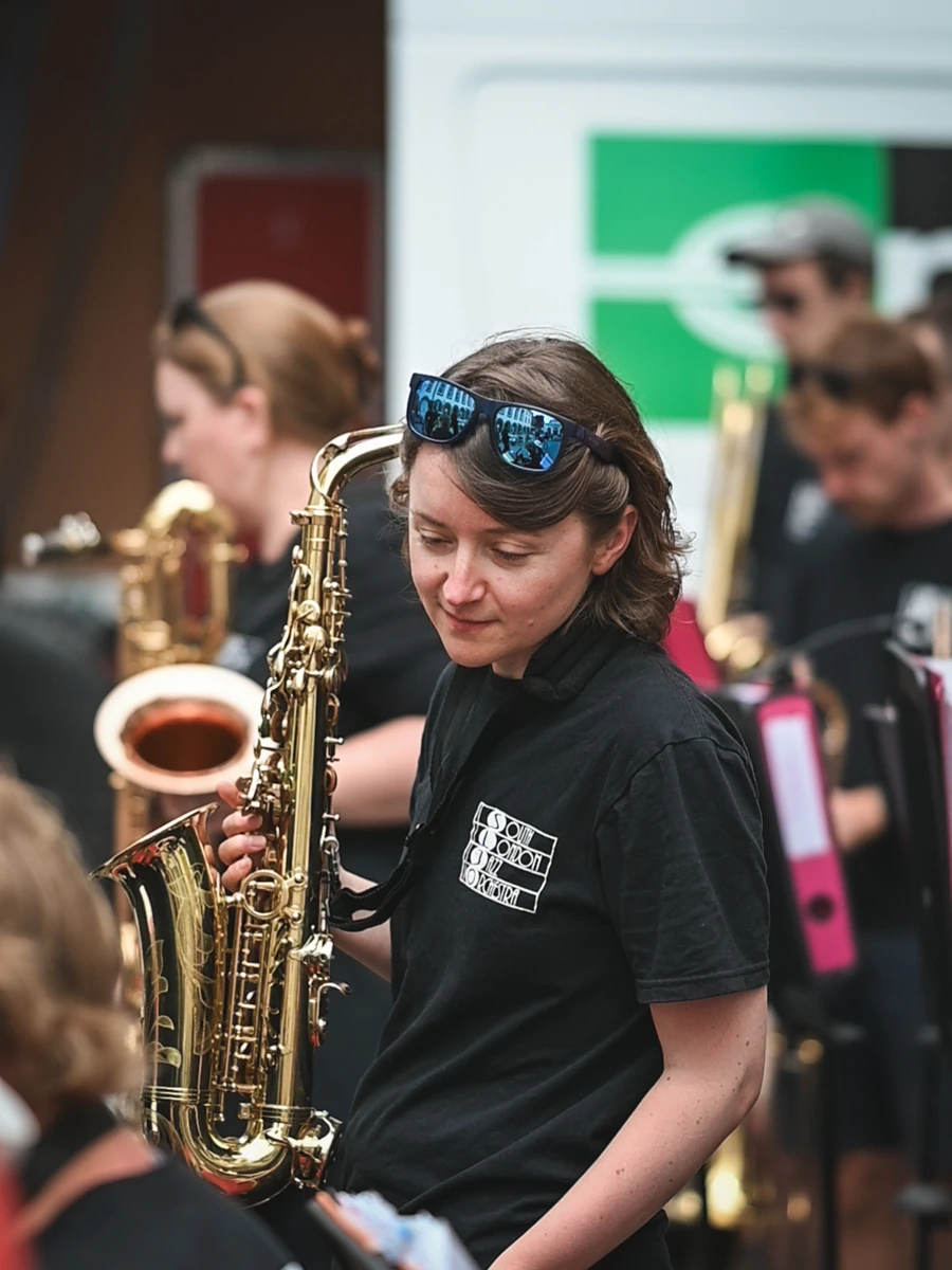 A jazz musician holding an alto sax moving around a crowded band