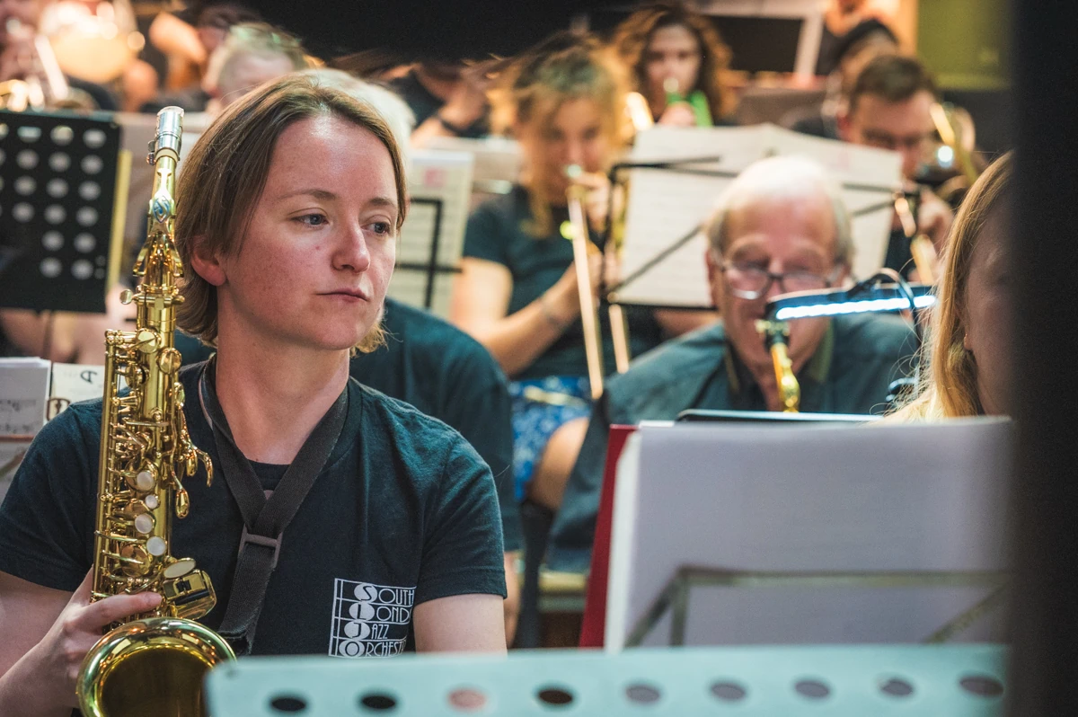 A jazz musician with an alto sax awaiting her turn to play