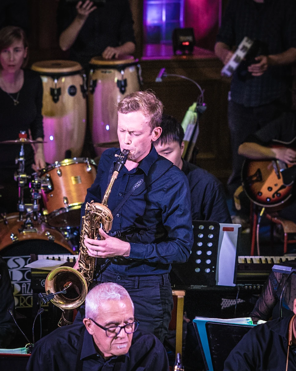 A jazz musician passionately playing a baritone saxophone in the middle of an improvised solo