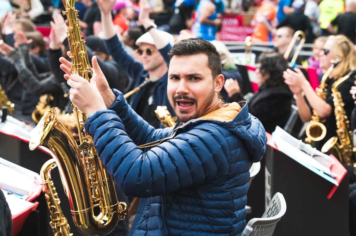 A jazz tenor sax player holding up his instrument in a band