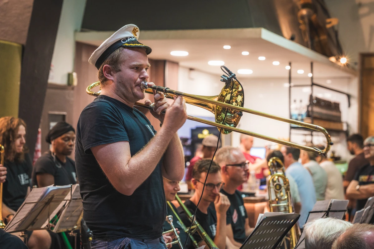 A jazz trombone player standing up and playing in a band