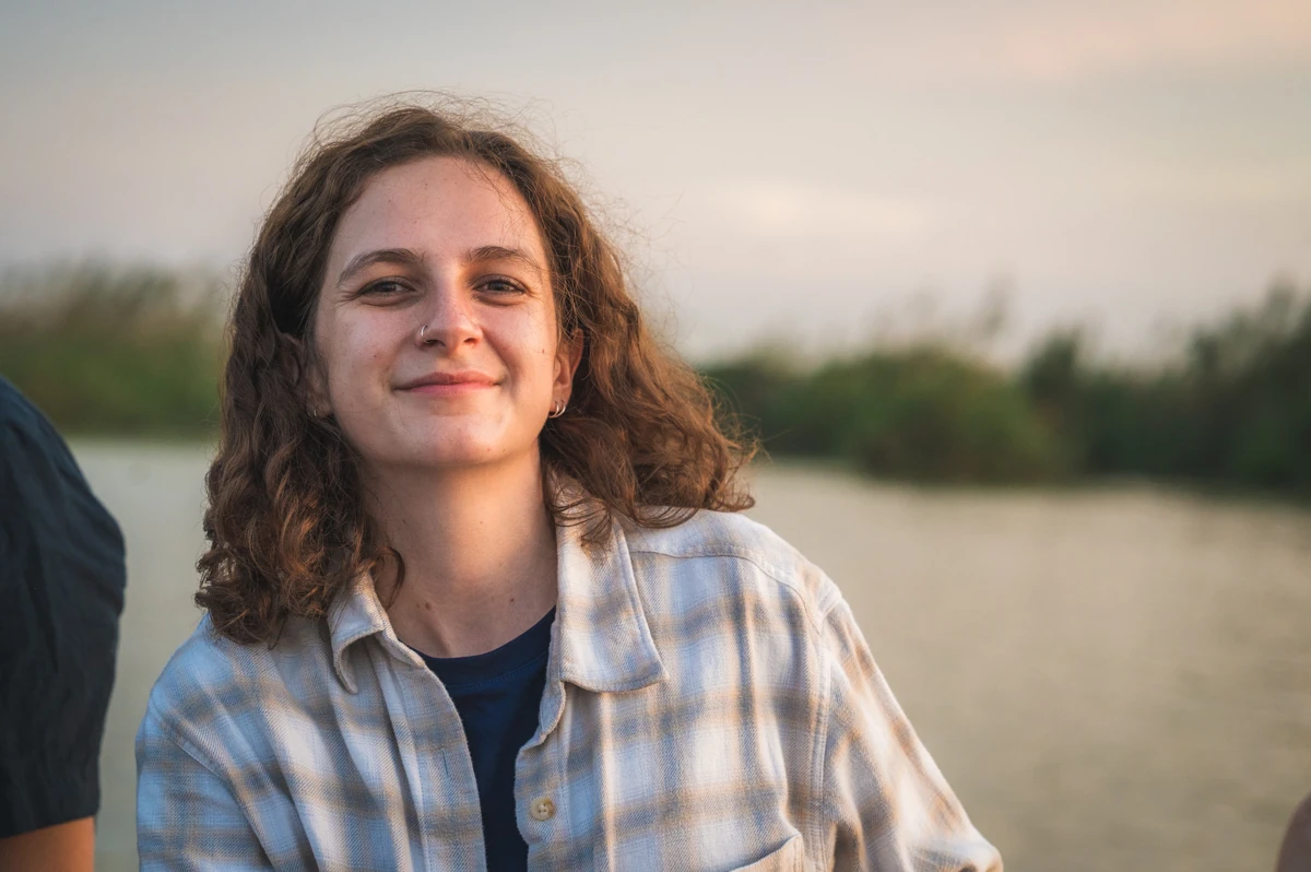A woman smiling on a boat during a colourful sunset