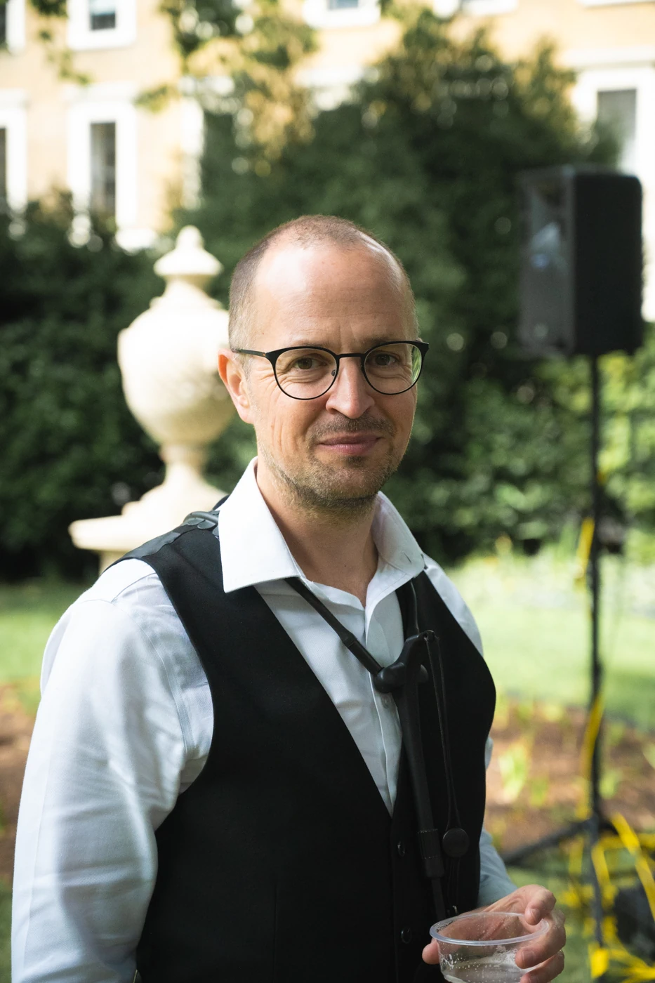 Man in a waistcoat in a garden smiling