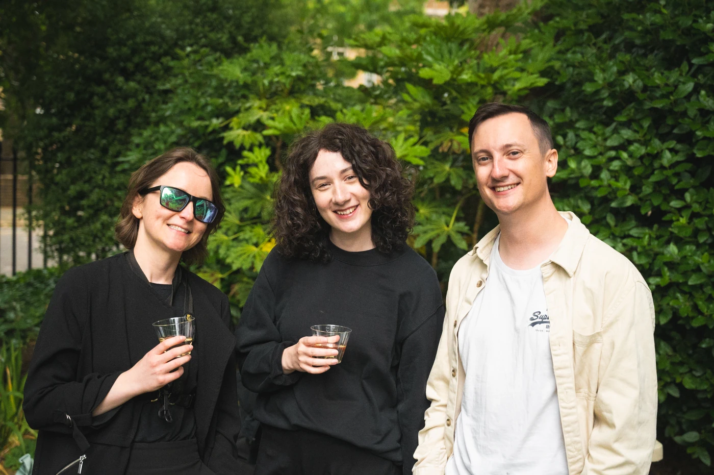 Three people in a garden, smiling at the camera