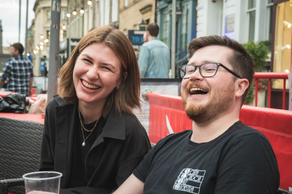 Two people in a social setting, laughing and smiling together