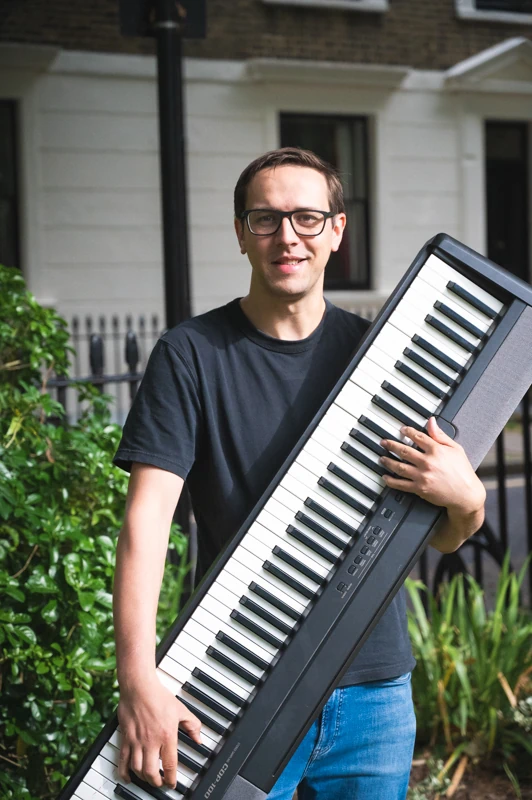 A musician holding up a keyboard in direct sunlight.