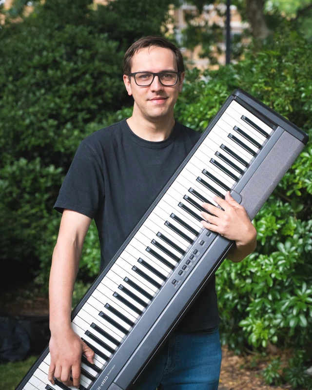 A musician holding up a keyboard in soft light.