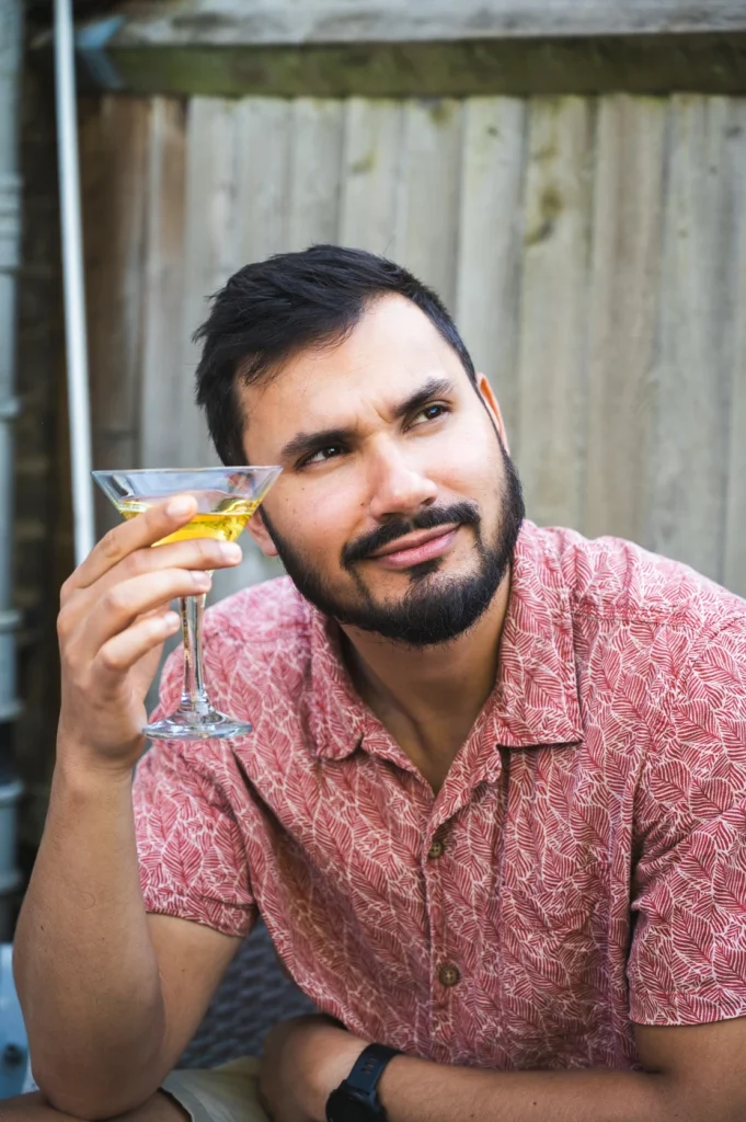 A man holding a cocktail and staring happily into the distance