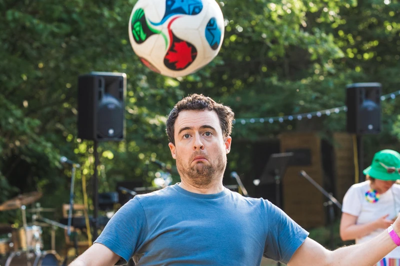 A man with a silly expression falling backwards and about to head a football