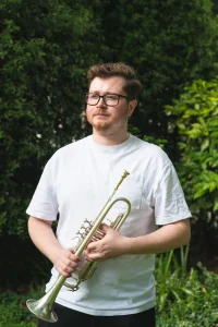 Man staring wistfully into the distance holding a trumpet
