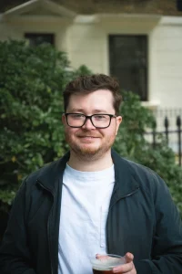 Man with glasses smiling in a garden in London