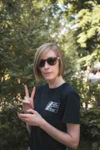 Woman in sunglasses holding a peace sign to the camera