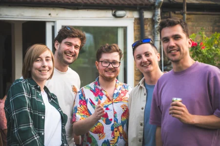 A group of 5 people at a social event, smiling and looking happy.